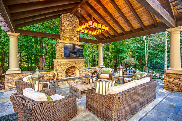 Custom outdoor living pavilion with stone fireplace and timber ceiling
